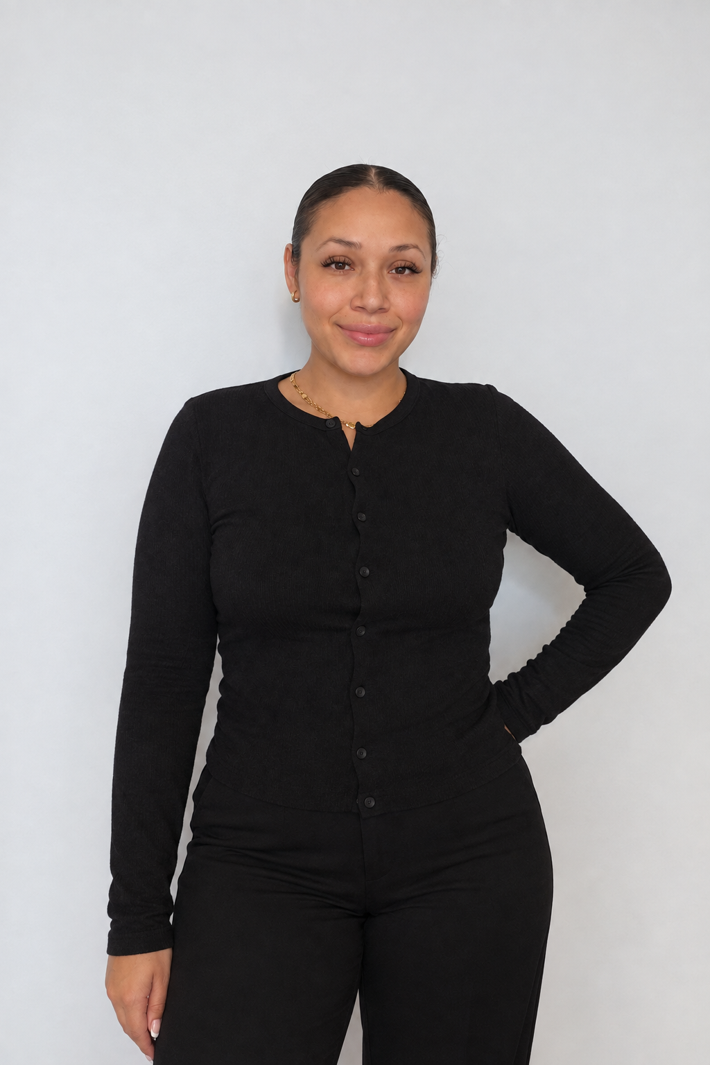 Lourdes, lash artist at Beauty Haus Toronto, smiling in a black cardigan